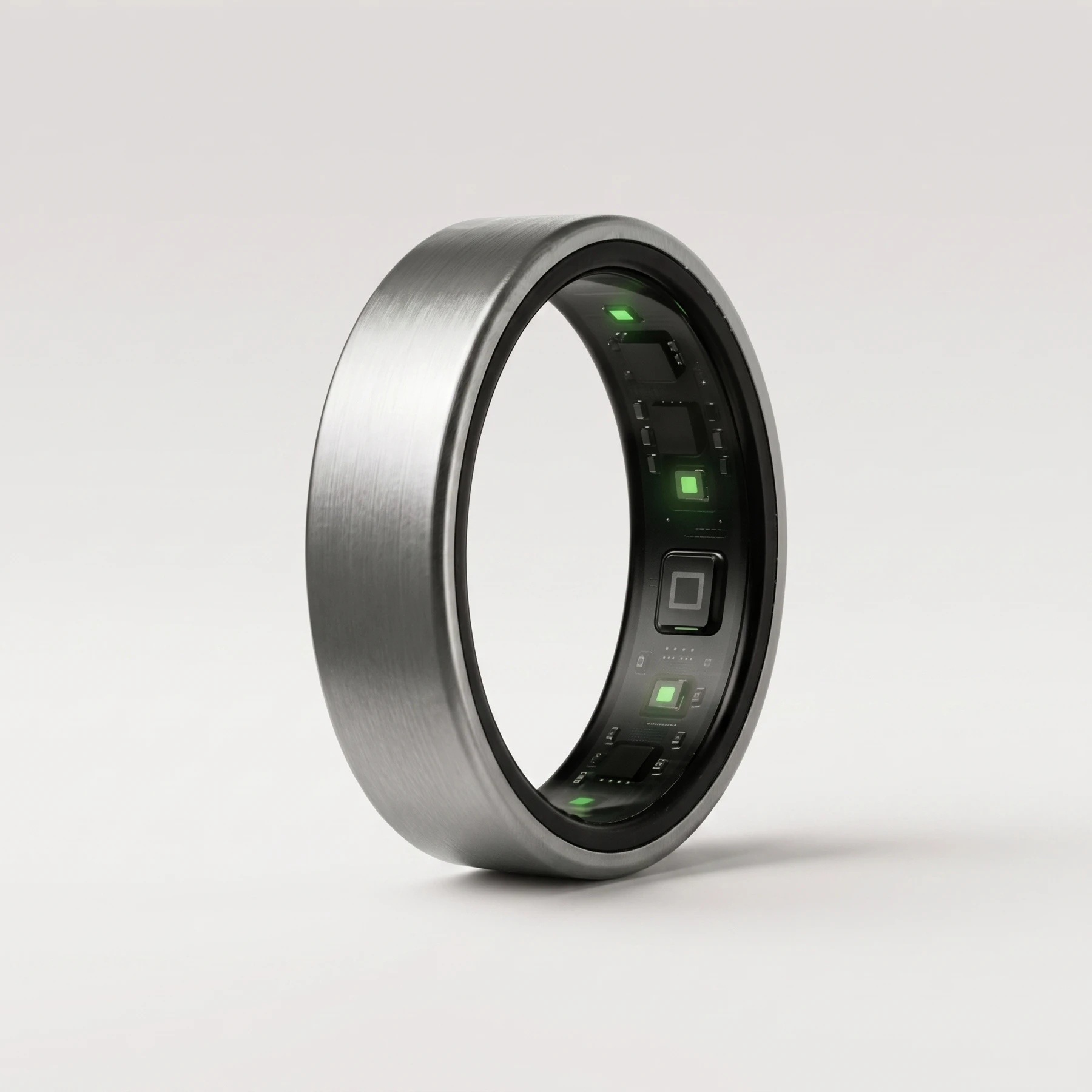 UbiRing in Lunar Silver: a brushed steel-grey titanium band, its inner sensor array lit green through the opening.